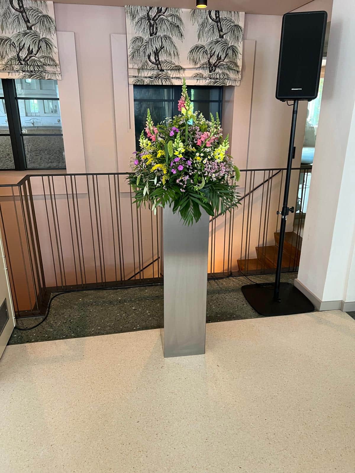 Grosses Blumenarrangement auf Edelstahlsaeule im Veranstaltungssaal