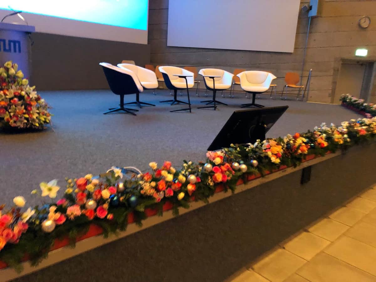 Buehnen-Blumenschmuck mit bunten Rosen und Weihnachtskugeln bei Firmenveranstaltung