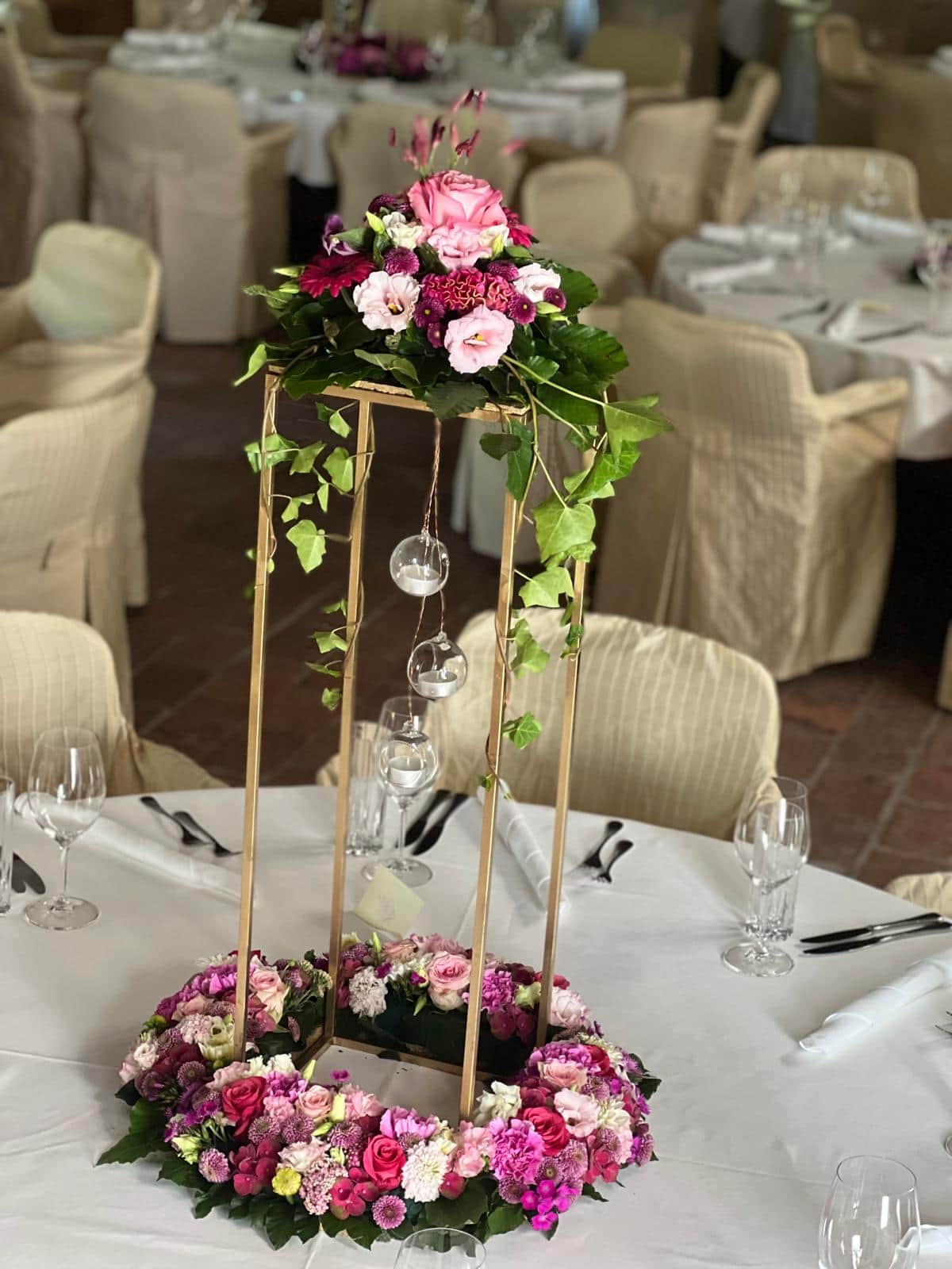 Festliches Tischgesteck mit rosa Rosen und Blumenkranz auf goldenem Staender