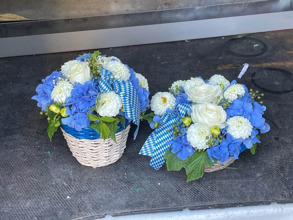 Weisse Blumenkoerbe mit blauen Hortensien und bayerischer Rautenschleife