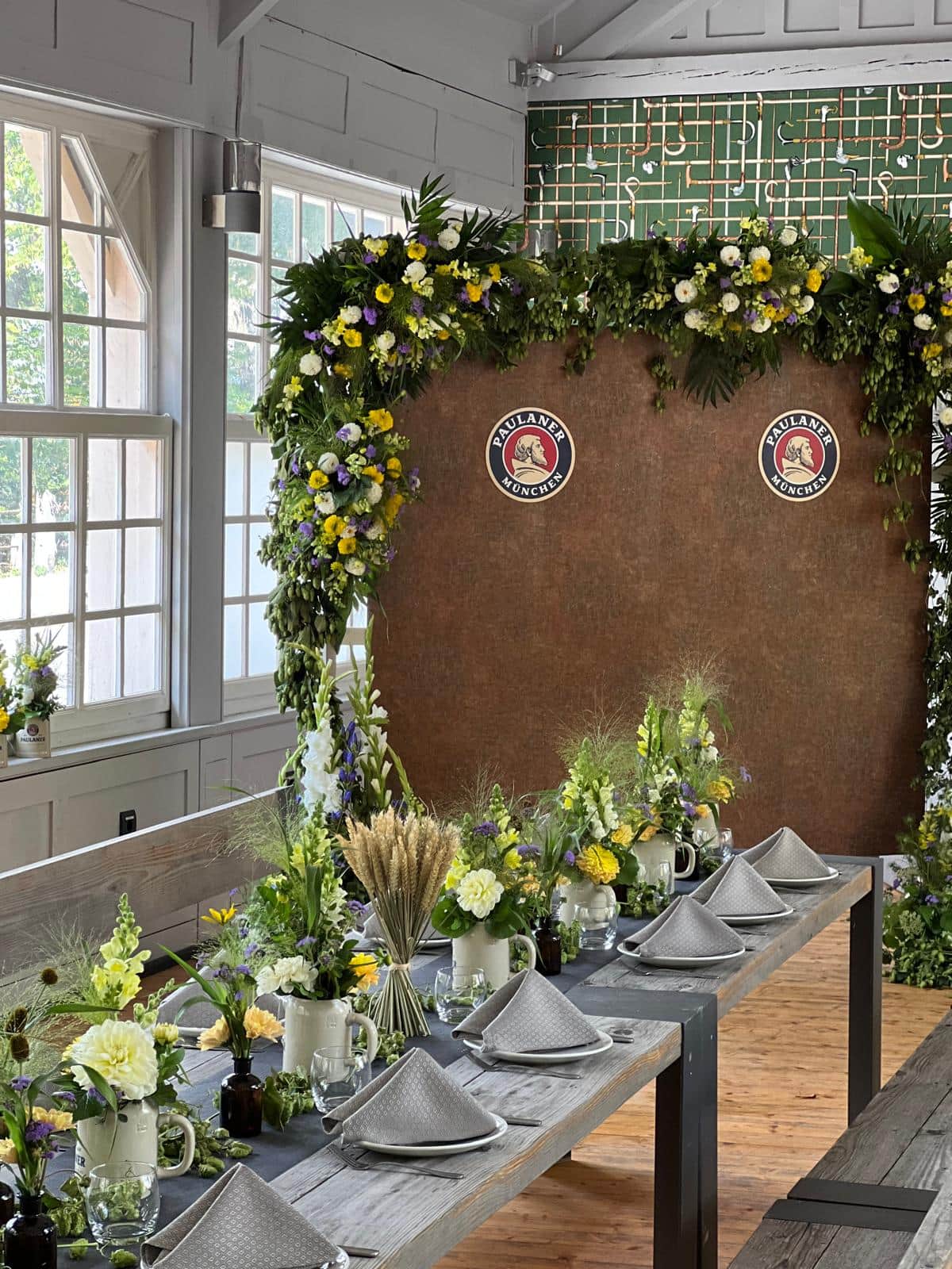 Festlich dekorierte Eventlocation mit Blumenbogen und Tischdeko