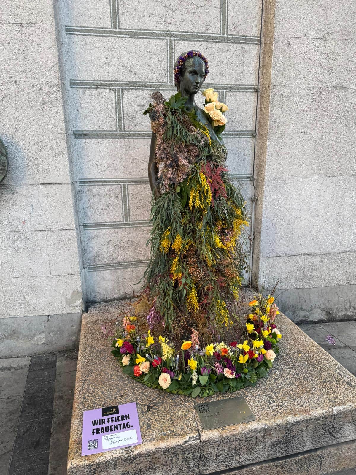 Bronzestatue geschmueckt mit einem Kleid aus frischen Blumen