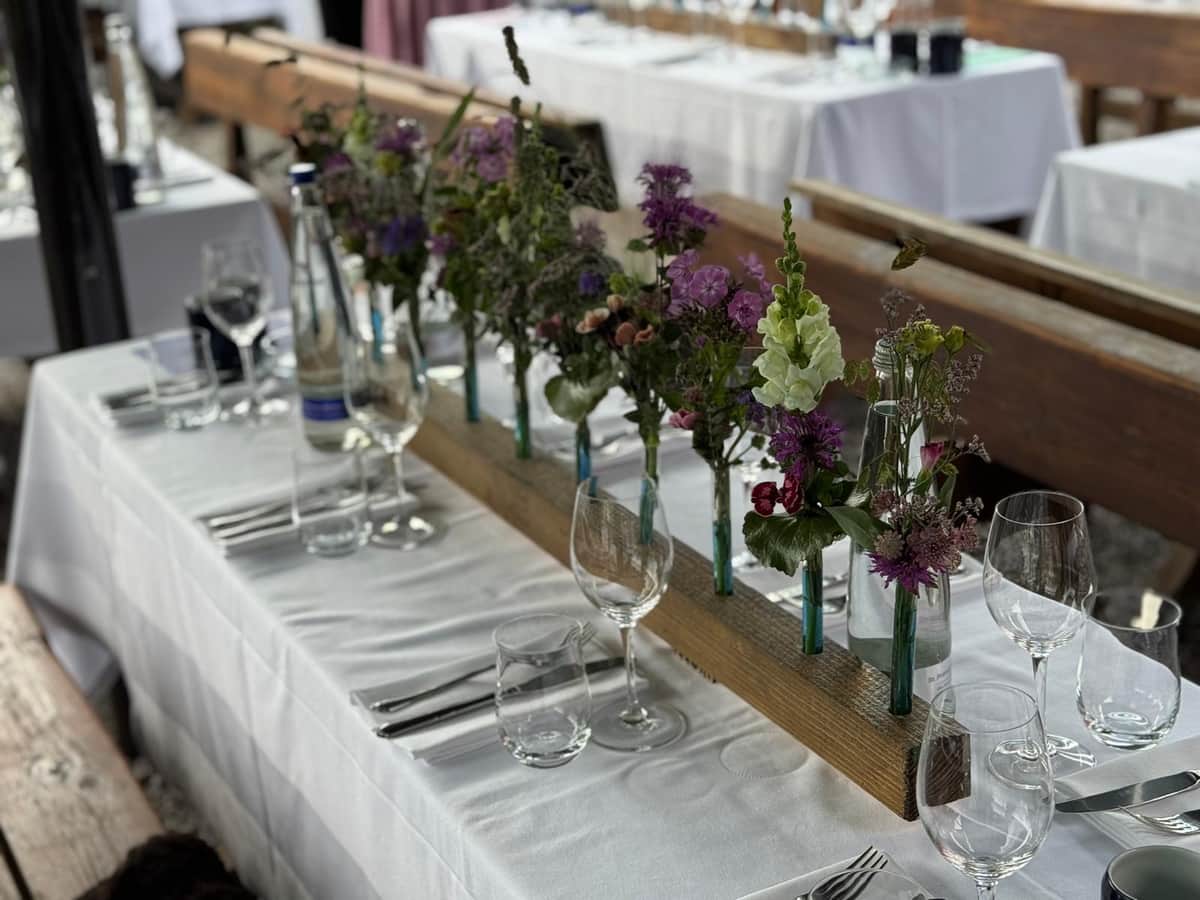 Biergarten-Festtafel mit Wiesenblumen in Reagenzglas-Vasen