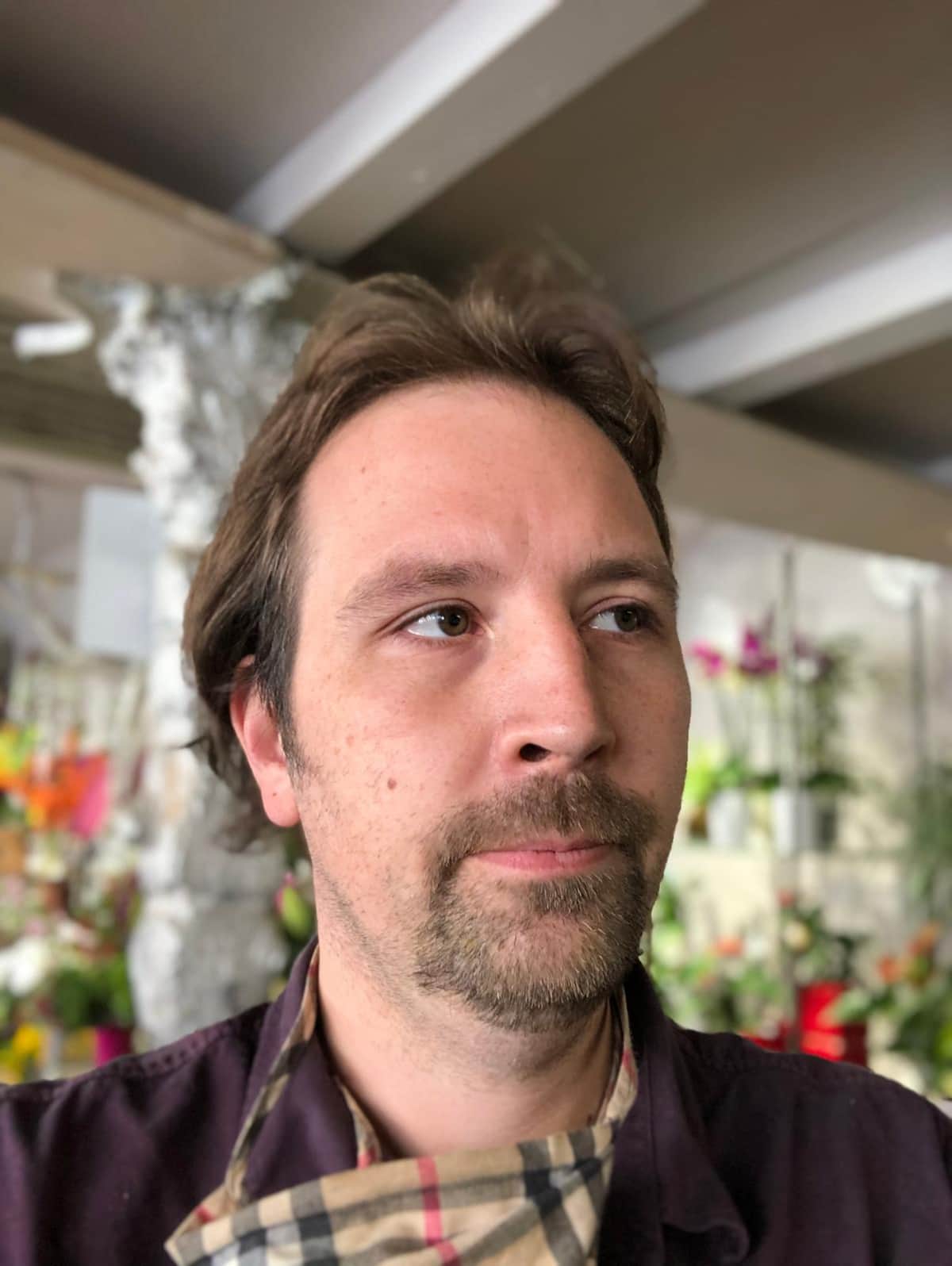 Florist mit Schuerze in seinem Blumenladen