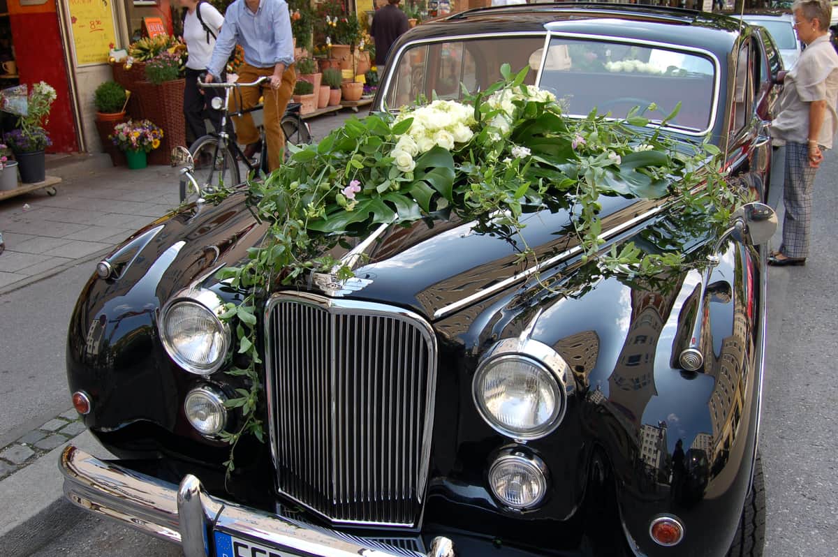 Schwarzer Oldtimer mit weißem Rosenschmuck und Efeu