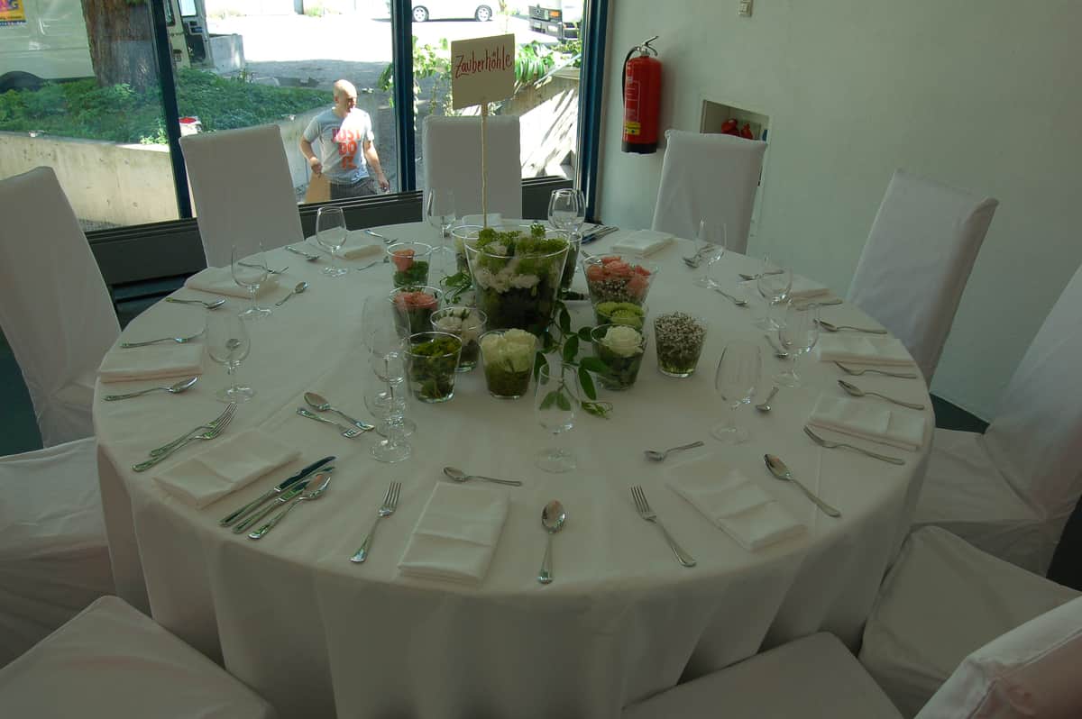 Runder Hochzeitstisch mit Glasvasen und Grün