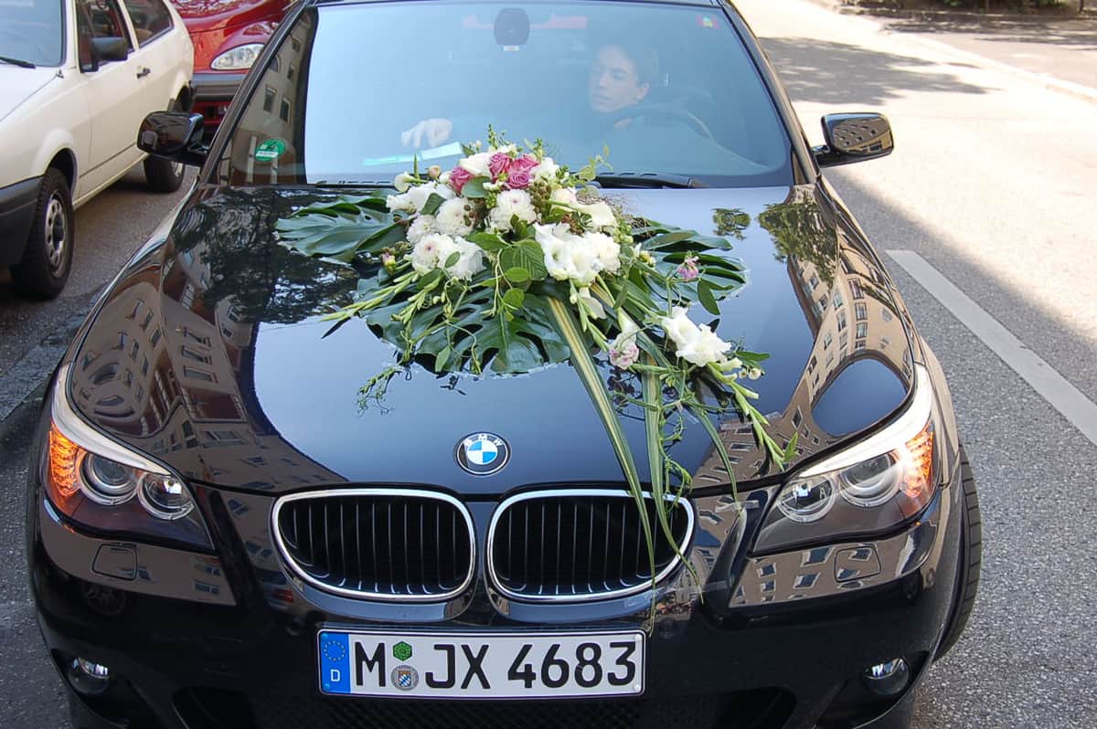Autoschmuck mit weißen Rosen auf schwarzem BMW