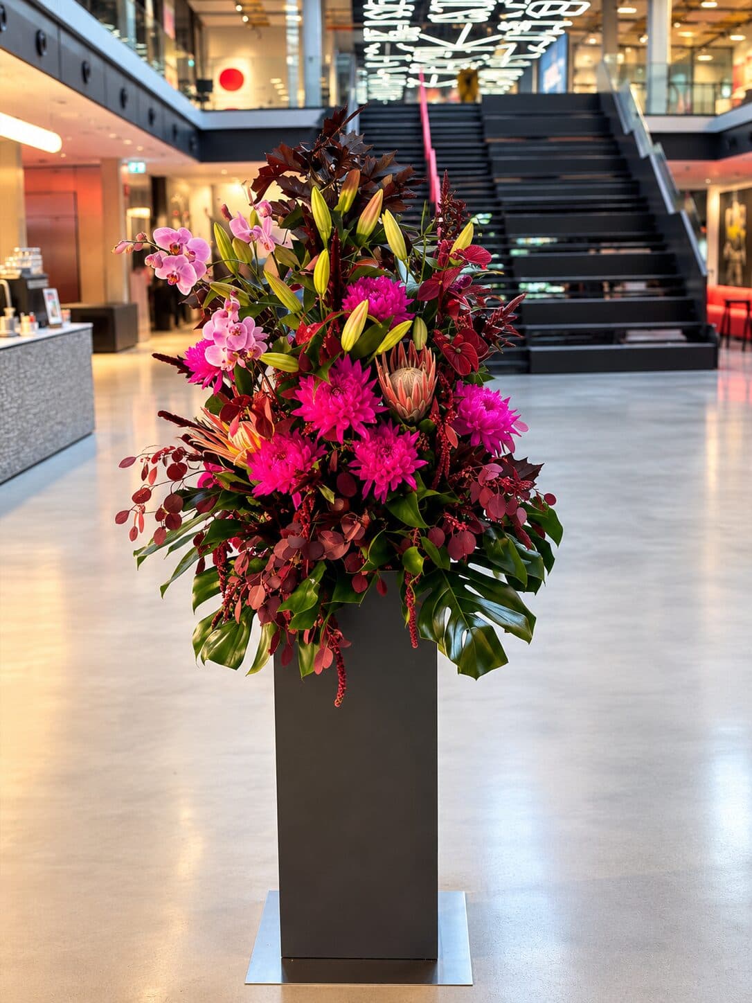Großes modernes Blumenarrangement in Magenta und Burgunder in einer Stehvase im Foyer des House of Communication München