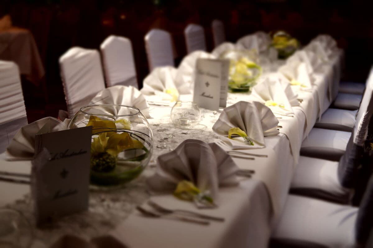 Festlich gedeckte Hochzeitstafel mit Calla-Arrangements in Glaskugeln und Platzkarten