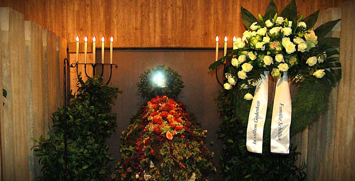 Bedruckte Trauerschleife an einem Kranz von Blumen Komander