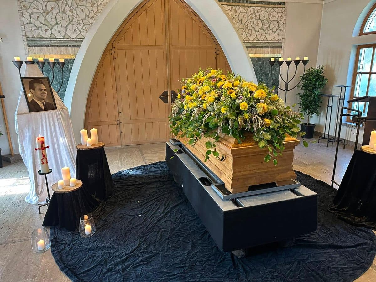 Gelbes Sargbukett mit Sonnenblumen auf einem Holzsarg in der Aussegnungshalle