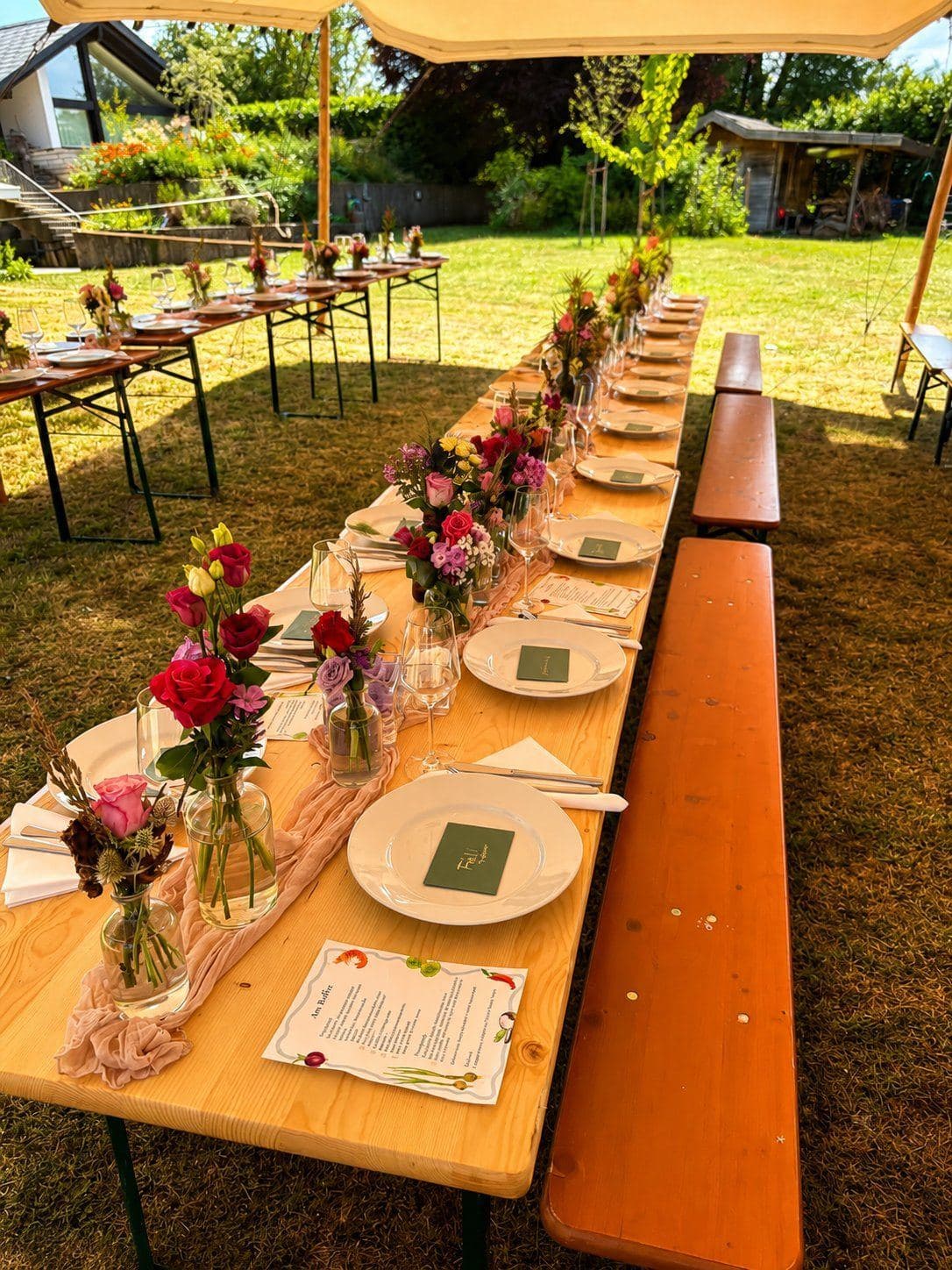 Lange Tafel im Garten mit sommerlicher Blumendeko
