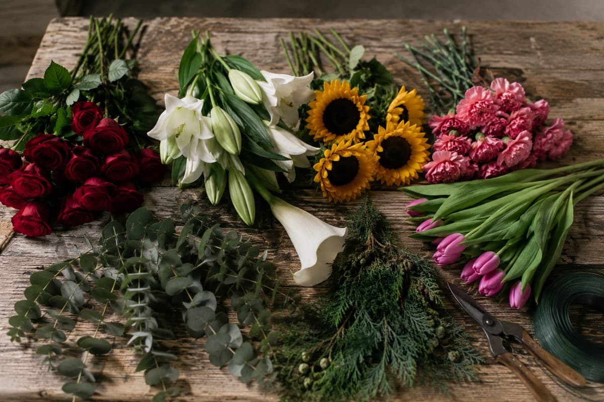 Trauerblumen auf der Werkbank: Rosen, Lilien, Sonnenblumen und Nelken